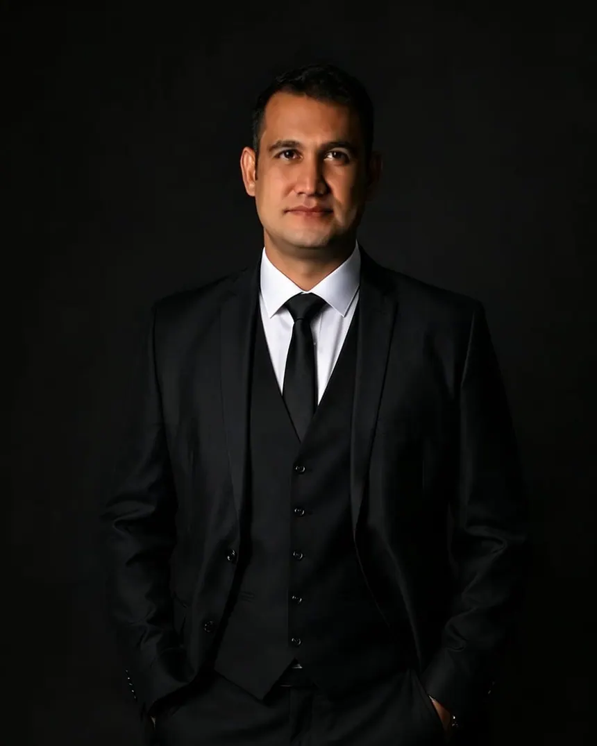 Hermeson Pires em pé, de terno preto, colete e gravata